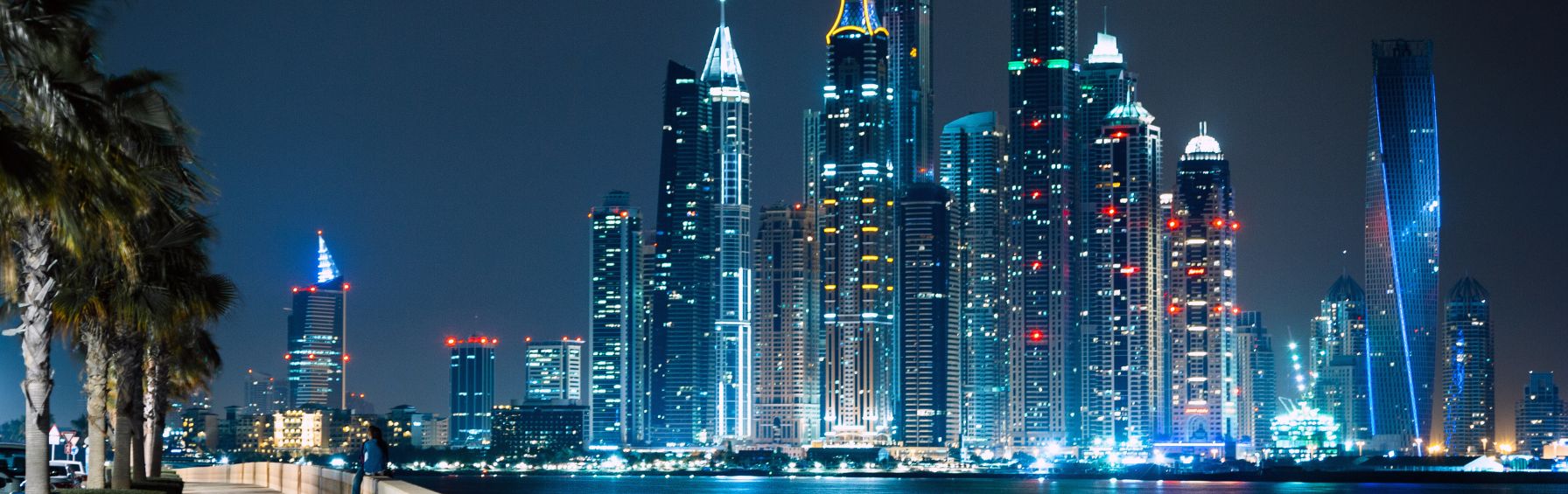 Blick auf die beeindruckende Skyline von Dubai bei Nacht mit den modernen Wolkenkratzern, die in der Freihandelszone Dubai liegen.