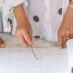 Die Szene vermittelt eine konzentrierte und professionelle Arbeitsatmosphäre, möglicherweise in einem Büro oder Planungsstudio, beispielsweise im Rahmen eines Projekts zum Thema Lebenshaltungskosten in Thailand, bei dem Planung und Analyse eine wichtige Rolle spielen.