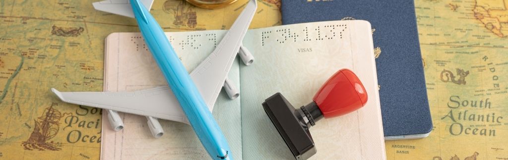Passeport ouvert avec tampon, avion miniature et carte du monde illustrant le visa affaire Singapour et les voyages d’affaires internationaux