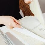 Persona che organizza documenti, inclusi il modulo TM7, per la gestione delle pratiche immigratorie in Thailandia.