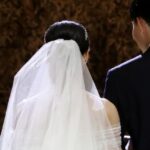 Heiraten in Thailand: Ein Brautpaar geht den Gang entlang, die Braut trägt einen Schleier und der Bräutigam einen Anzug.