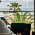 Professionnel travaillant à distance face à la mer depuis un appartement en Thaïlande illustrant le visa télétravail Thaïlande pour expatriés et travailleurs à distance