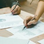 Entrepreneur in Thailand working with a business team to analyze financial data and charts, reviewing reports for strategic decision-making.