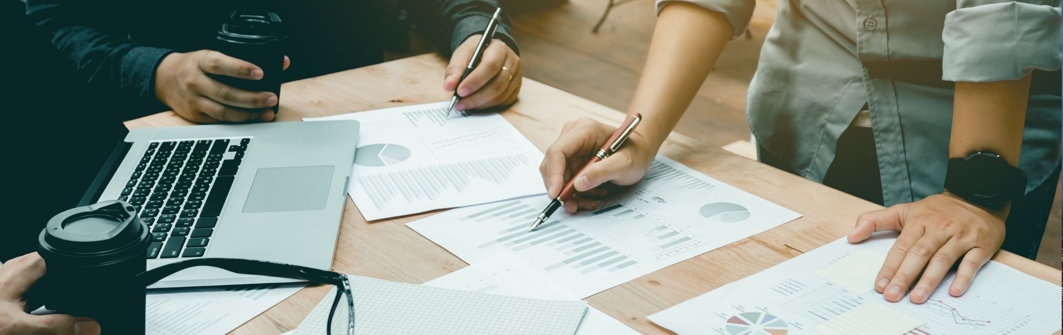 Entrepreneur in Thailand working with a business team to analyze financial data and charts, reviewing reports for strategic decision-making.