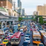 Circulation à Bangkok avec des taxis, bus et voitures, soulignant l'importance du code de la route en Thaïlande pour une conduite sûre dans les grandes villes.