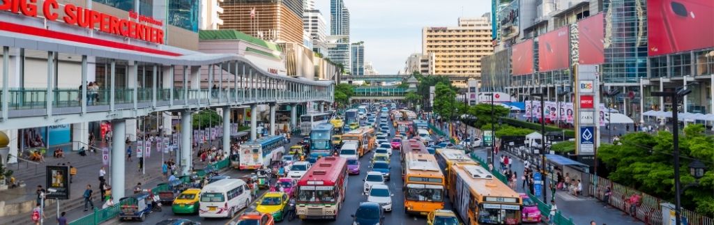 Circulation à Bangkok avec des taxis, bus et voitures, soulignant l'importance du code de la route en Thaïlande pour une conduite sûre dans les grandes villes.
