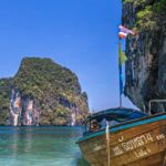 Ist es sicher nach Thailand zu fliegen – traumhafte Küstenlandschaft mit traditionellen Booten und beliebten Reisezielen in Thailand.