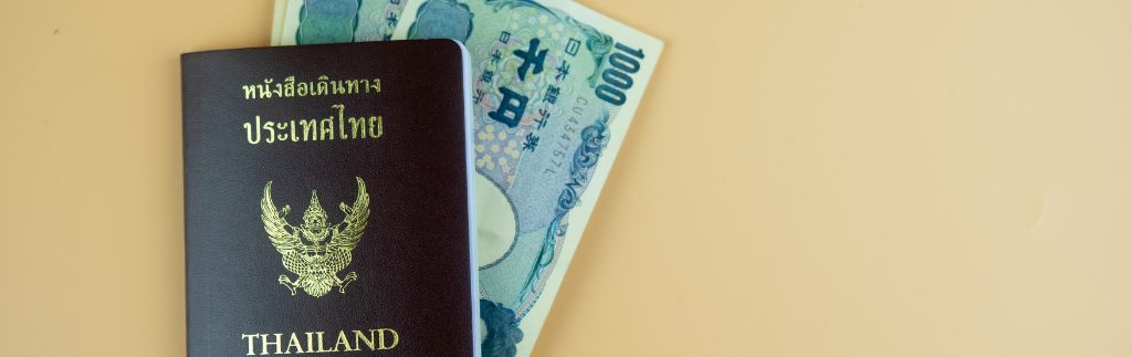 Passeport thaïlandais avec billets illustrant le durcissement de l’obtention du visa en Thaïlande
