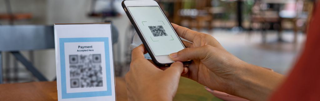 Person scanning a QR code payment in a restaurant in Thailand