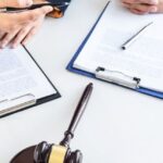 Two legal professionals reviewing documents beside a judge’s gavel and scales of justice, representing an expatriate lawyer in Thailand providing legal services for foreigners and expats.