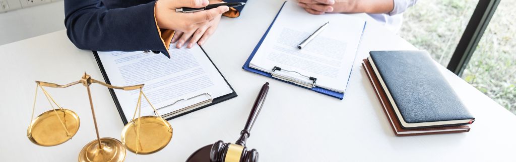 Two legal professionals reviewing documents beside a judge’s gavel and scales of justice, representing an expatriate lawyer in Thailand providing legal services for foreigners and expats.