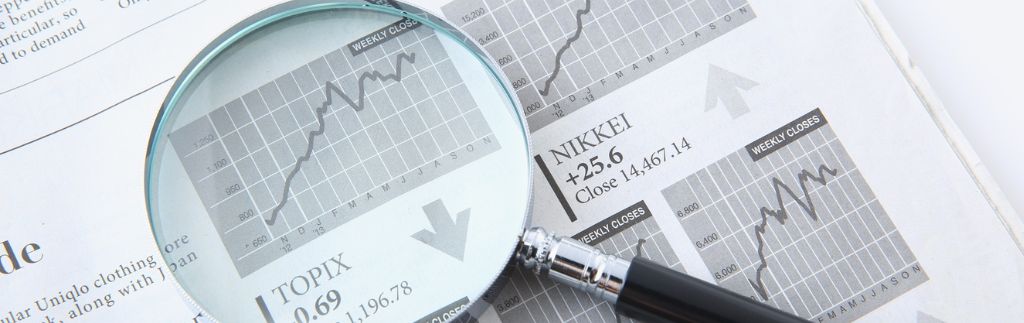 Jahresabschlüsse – Lupe über Finanzdiagrammen und Börsendaten als Symbol für Bilanzanalyse, Geschäftsberichte und Unternehmensfinanzen.