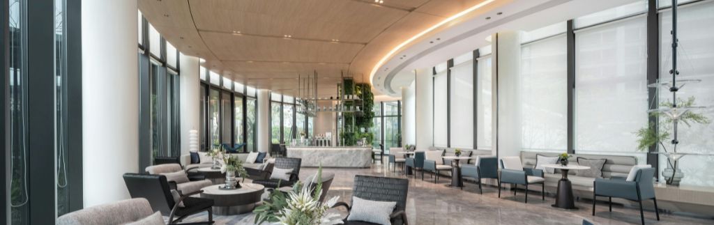 Hotel Thailandia – elegante lobby di hotel moderno con design raffinato, ampie vetrate e area relax luminosa.